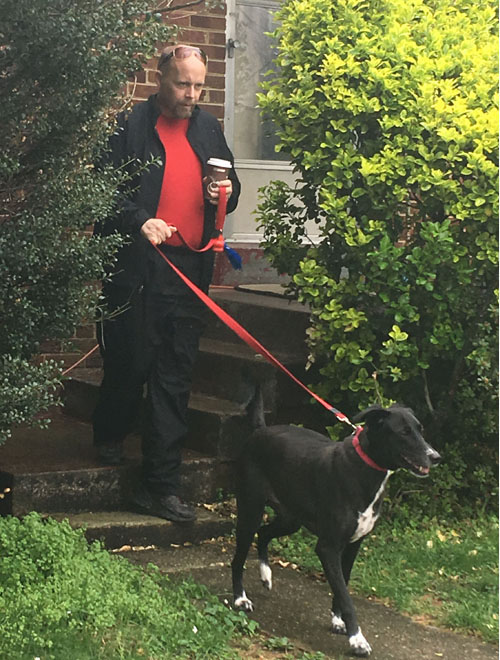 Paul is walking out of his house with his dog Blackie on a leash.